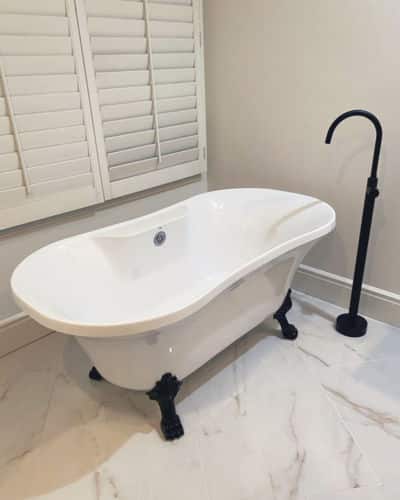 Prefer a bathtub only? Pictured is a white clawfoot, stand-alone bathtub with a black faucet and claw feet. 