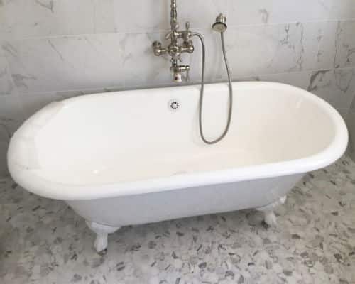 Modern, all white clawfoot tub set on top of white, hexagonal, tile flooring. 