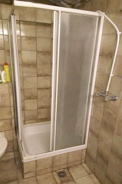 The DIY shower remodel has many issues. The base is built up above ground but the drain is on the outside of the shower, the knobs and spout are also outside of the enclosed shower. 