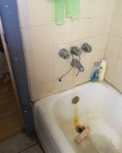 Scary Bathroom - An old bathtub with a yellow streak of rust trailing from the faucet to the tub drain.