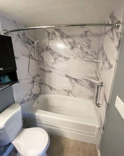 Marble Bathroom: A standard bathtub shower combo with marble Calacatta pattern walls. 