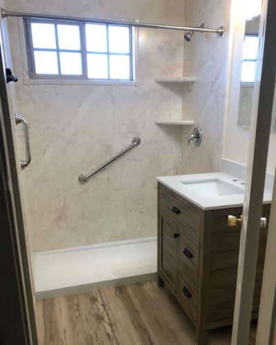 8 Before and After Bathroom Remodel Photos : this after photo shows a walk-in shower, with a low-threshold shower base. The walls are now covered with Sentrel material in Alaskan Ivory, a beautiful neutral stone pattern.