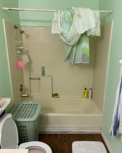 8 Before and After Bathroom Remodel Photos : A standard bathtub and shower combo with yellowed tub and wall panels.