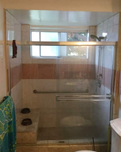8 Before and After Bathroom Remodel Photos : A walk-in shower with old larger tiled walls and a salmon colored accent strip across the middle.